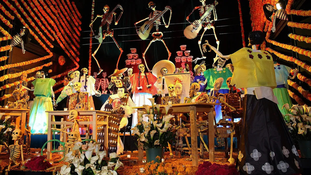 Altar monumental de Día de Muertos con esqueletos músicos, catrinas y flores de cempasúchil