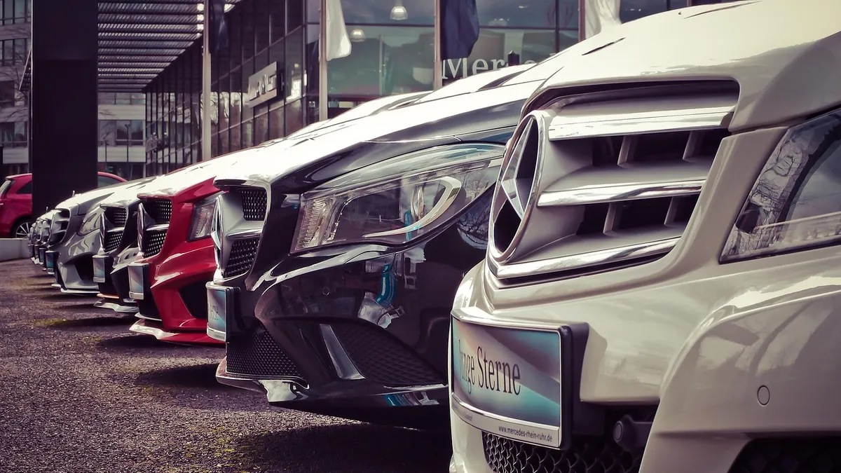 Una fila de autos nuevos estacionados frente a una agencia