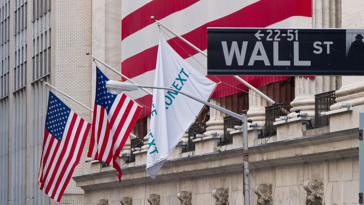 Façade de la Bourse de New York pavoisée de drapeaux américains, sous le panneau Wall Street